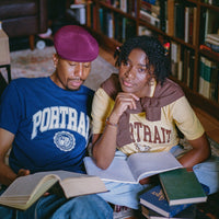 Two people sitting on a couch with books in a room filled with bookshelves.